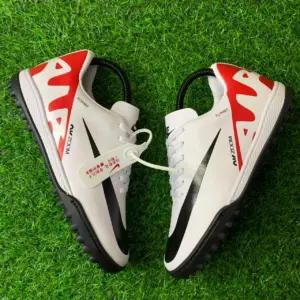 Tenis Nike Mercurial Vapor 15 Academy TF blancos con detalles rojos y negros sobre césped sintético, con suela de tacos y tecnología Air Zoom.